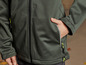 Une veste softshell verte avec des fermetures éclair jaunes et un logo de marque.