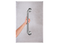 Une main tient une barre d'appui en métal argenté fixée à un mur.