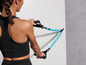 Une femme en tenue de sport utilise un élastique bleu pour s'entraîner.
