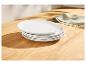 Assiettes blanches empilées sur une table en bois avec un torchon vert.