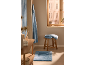 Serviettes de bain bleues et tapis de bain dans une salle de bain chaleureuse avec un tabouret en bois.