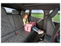 Un enfant dans une voiture avec un sac rose rempli de jouets.