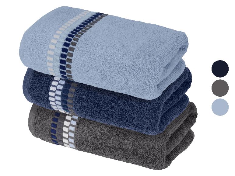 Pile de trois serviettes pliées en bleu clair, bleu foncé et gris avec des motifs rayés.
