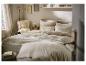 Chambre à coucher avec lit, linge de lit aspect lin, coussins décoratifs et petite table d'appoint.