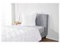 Une couette et un oreiller blancs à motif quadrillé sur un lit gris.