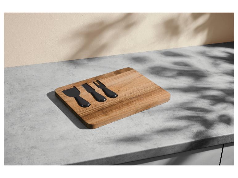 Planche à fromage en bois avec trois couteaux noirs sur un comptoir gris.