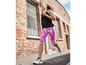 Une femme vêtue de vêtements de sport Under Armour court le long d'un bâtiment en brique.