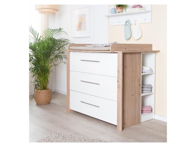 Commode à langer en bois avec tiroirs blancs et étagères ouvertes dans une pièce lumineuse.
