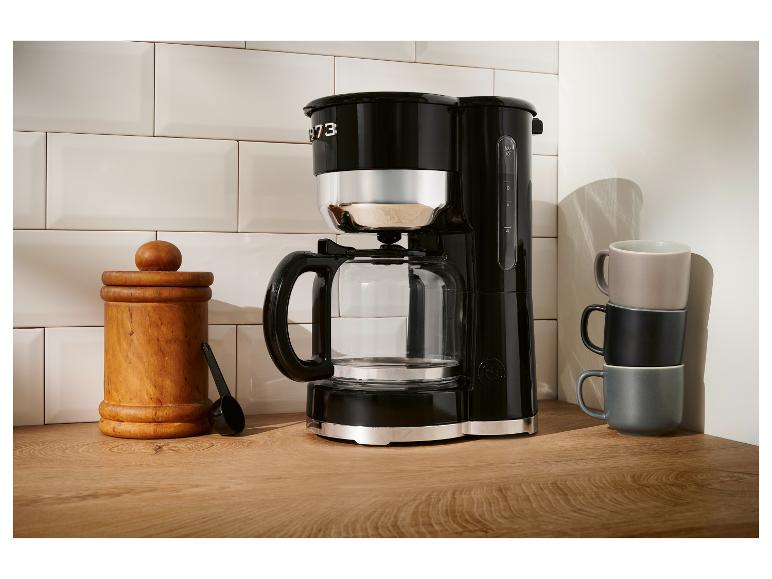 Cafetière Smeg noire sur un comptoir en bois.