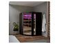 Sauna moderne avec éclairage violet, une plante et un peignoir blanc dans une salle de bain.