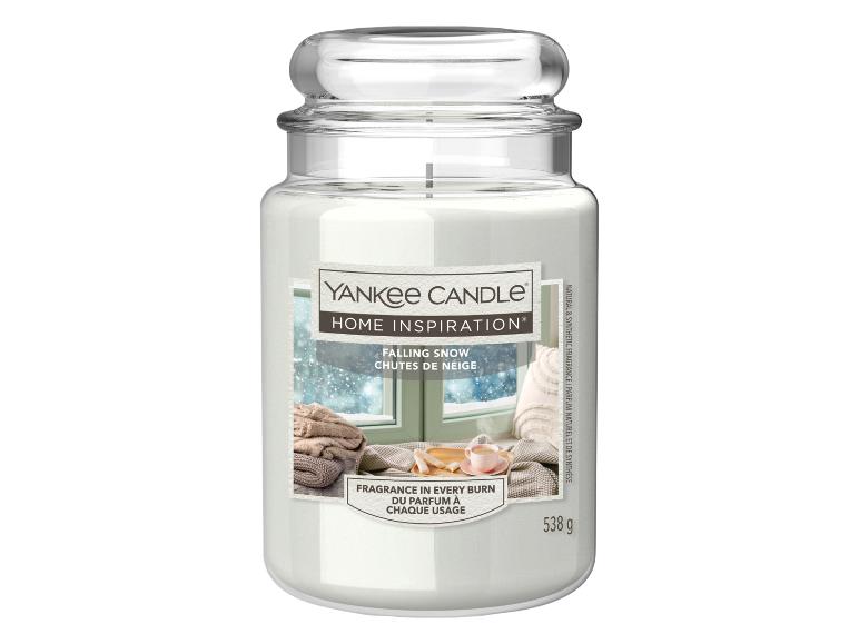 Bougie blanche dans un pot en verre avec une étiquette montrant une scène de fenêtre enneigée, intitulée « Falling Snow ».
