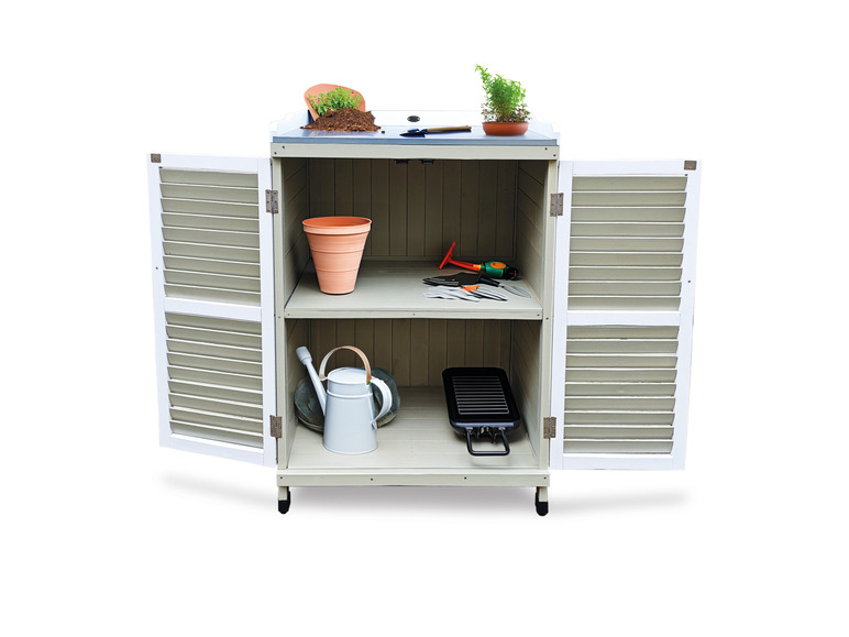 Un abri de jardin en bois blanc avec un arrosoir, des outils et un grill.