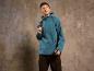 Un homme portant une veste softshell bleue et un pantalon cargo noir.