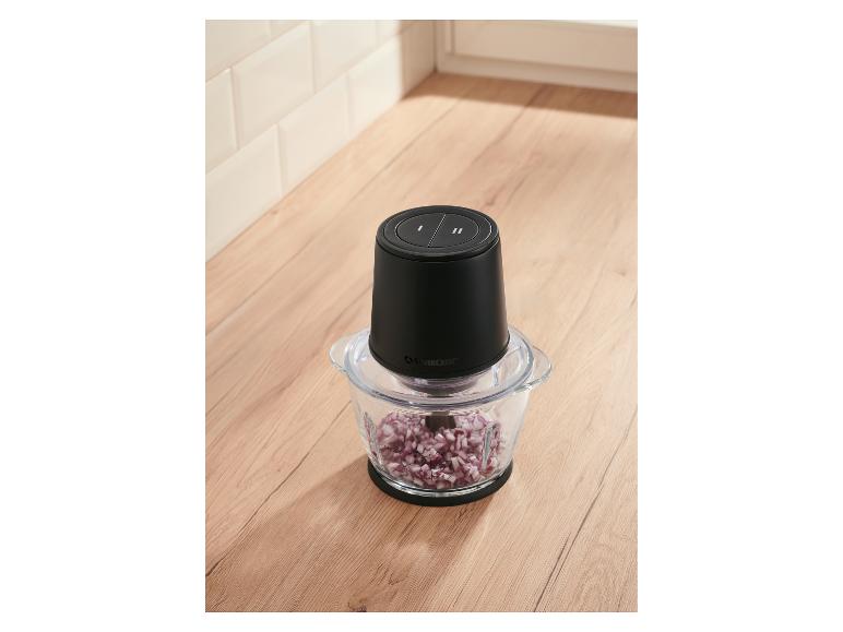 Hachoir à aliments avec des oignons rouges coupés en dés sur un comptoir de cuisine en bois.