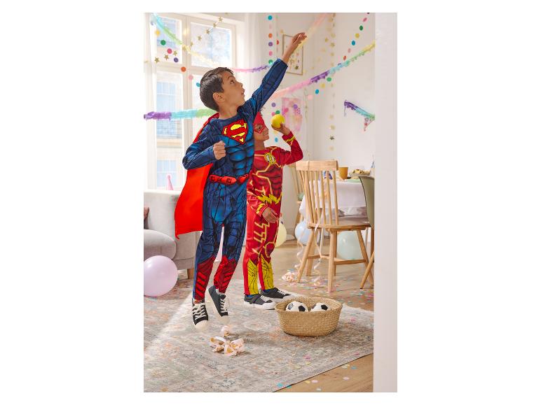 Deux enfants en costumes de super-héros jouent à une fête avec des confettis et des ballons.