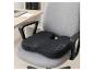 Coussin de siège noir avec découpe coccyx sur chaise de bureau grise, bureau en arrière-plan.