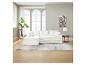 Canapé modulaire blanc avec coussins, tapis gris et plante dans un salon lumineux.
