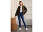 Une femme porte une veste en jean verte avec un jean skinny bleu.