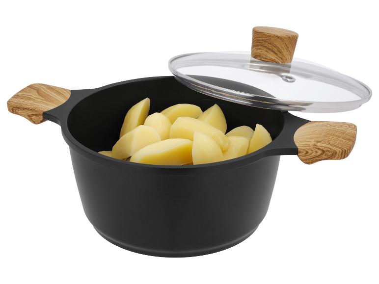 Marmite noire avec poignées en bois, couvercle en verre et pommes de terre pelées
