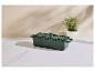 Cocotte rectangulaire en fonte verte avec couvercle et plante en pot sur une surface en marbre blanc.