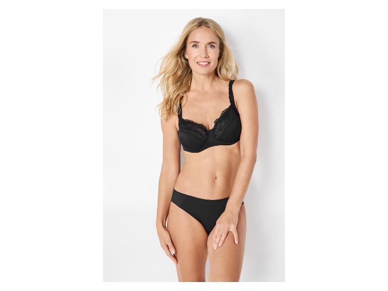 Femme souriante en soutien-gorge et culotte en dentelle noire.