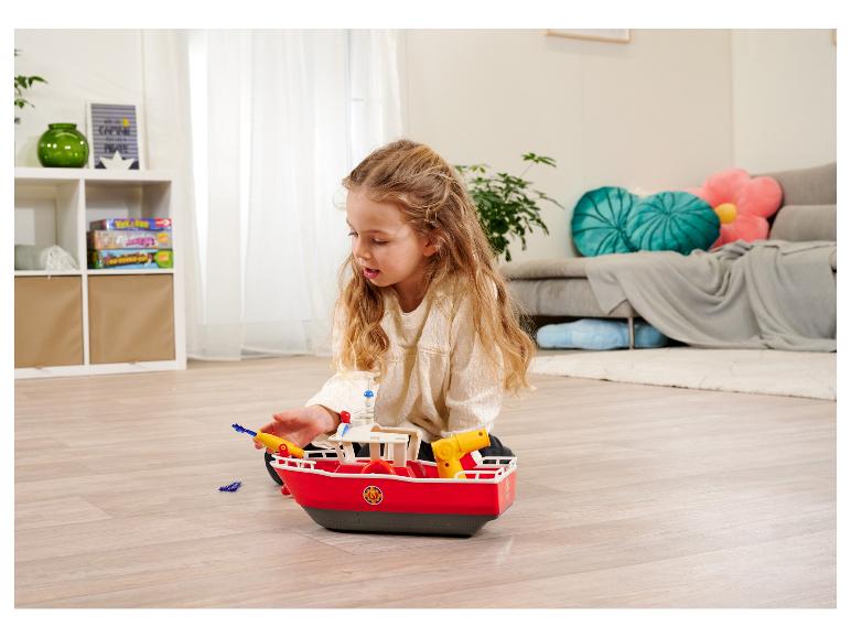 Une fillette joue avec un bateau jouet Playmobil.