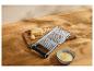 Râpe à fromage avec fromage râpé et un morceau de fromage sur une planche en bois.