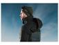Homme en veste Crivit noire à capuche, bonnet et masque de ski devant un ciel bleu.