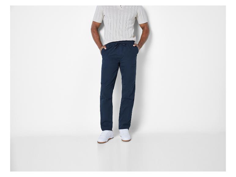 Homme portant un pantalon bleu à cordon et des baskets blanches.