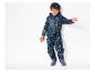 Un enfant porte une combinaison de pluie bleue avec un motif de tigres et d'éléphants.