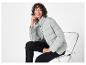 Une femme porte une veste gris clair et un pantalon noir.