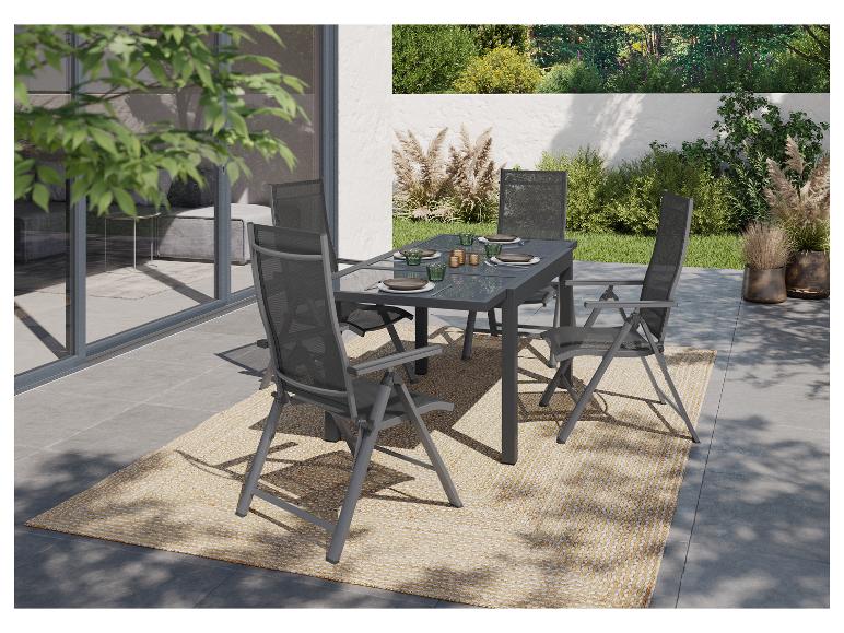 Ensemble de salle à manger extérieur avec table gris foncé et quatre chaises sur un tapis tressé sur une terrasse.