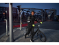 Homme en doudoune et pantalon de sport avec gants et casque, poussant un vélo la nuit.