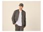Homme en veste bomber gris foncé, t-shirt blanc, pantalon de survêtement assorti et casquette.