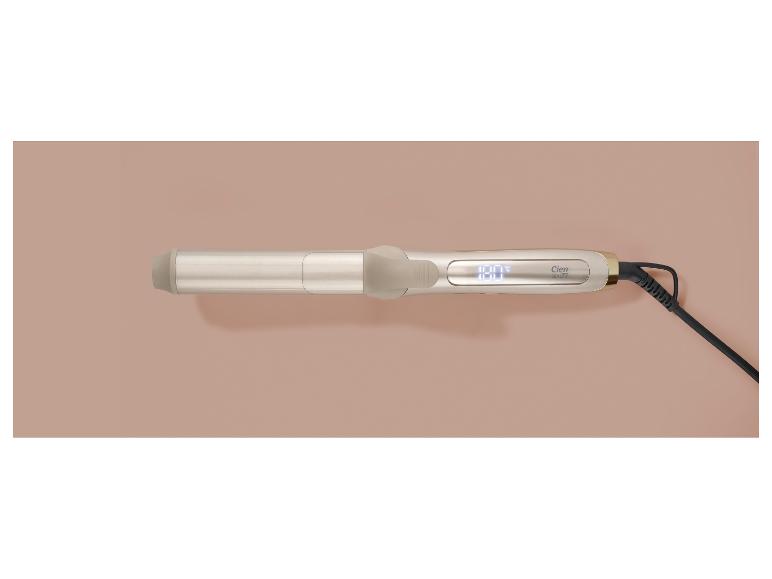 Fer à friser doré avec écran numérique et cordon noir sur fond beige.