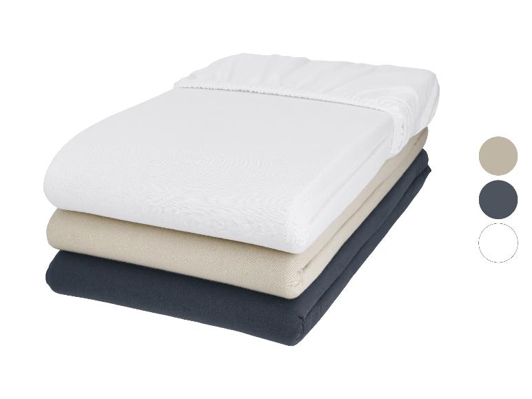 Lot de trois draps-housses en blanc, beige et gris foncé.