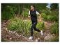 Femme courant en pleine nature avec un legging noir et un gilet Kalenji.