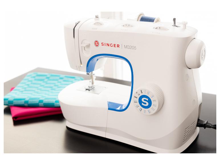 Machine à coudre blanche avec accents bleus, une bobine de fil bleu et des tissus colorés