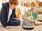 Un chaton joue avec un jouet pour chat en forme d'assiette, tandis qu'un garçon et une fille regardent.