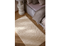 Tapis beige avec motif de roses en relief dans une chambre avec lit et table de chevet.