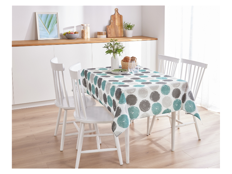 Une table de cuisine blanche avec une nappe à pois ronds et des chaises blanches.