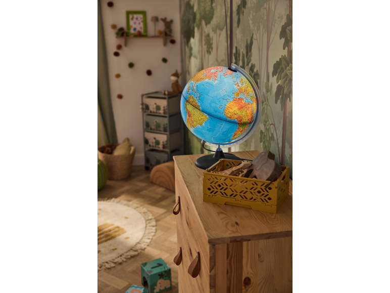 Globe terrestre lumineux sur une commode en bois dans une chambre d'enfant thème forêt.