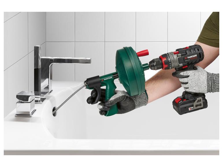 Déboucheur de canalisations et perceuse-visseuse sans fil utilisés pour déboucher un lavabo.
