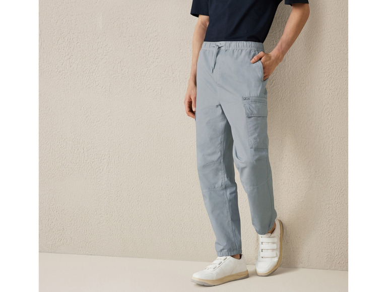 Homme portant un pantalon cargo bleu et des baskets blanches.