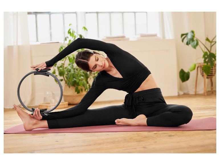 Une femme faisant des exercices de pilates avec un anneau sur un tapis de yoga.