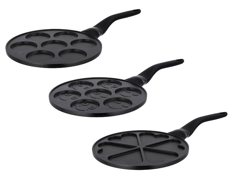 Trois poêles à crêpes noires avec différentes formes : rondes, souriantes et cœur.