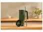 Mug thermique vert avec anse et paille sur un comptoir en bois, couvercle avec texte