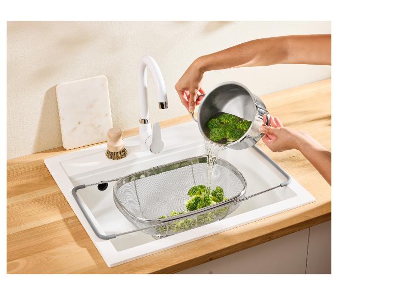 Personne versant du brocoli d'une casserole dans une passoire dans l'évier de la cuisine.