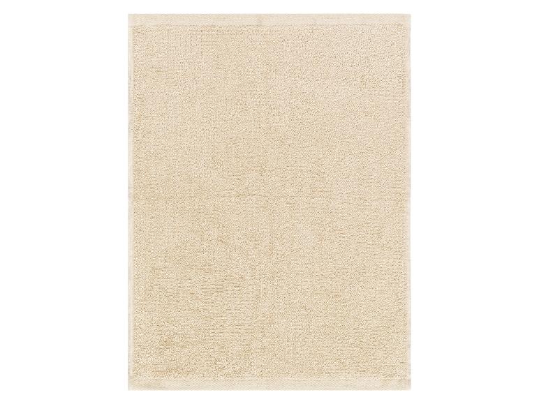 Serviette de bain beige en tissu éponge.