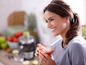 Une femme savoure un verre de jus dans la cuisine.
